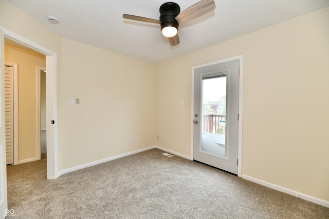 carpeted spare room featuring ceiling fan, visible vents, and baseboards