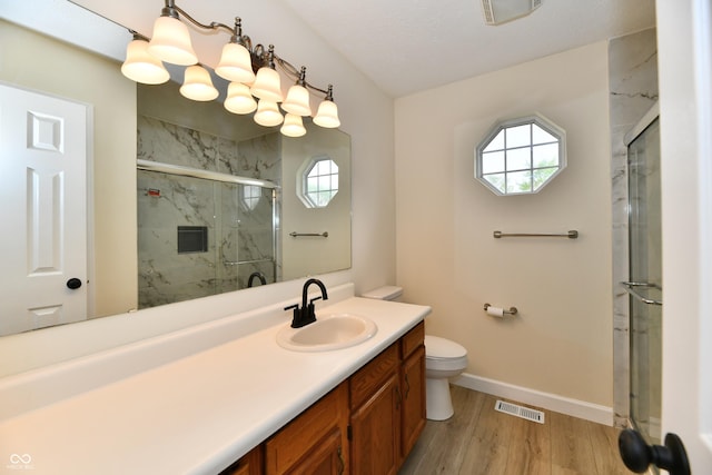 bathroom with a marble finish shower, baseboards, wood finished floors, and visible vents