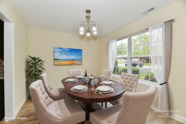 dining space with baseboards, visible vents, an inviting chandelier, and light wood finished floors