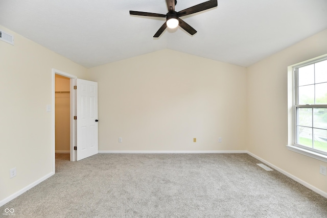 carpeted empty room featuring ceiling fan, visible vents, baseboards, and lofted ceiling