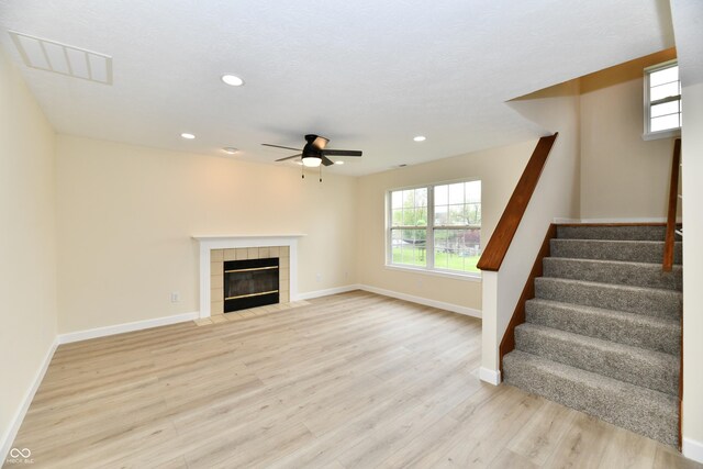 unfurnished living room with visible vents, baseboards, ceiling fan, stairway, and light wood-style flooring