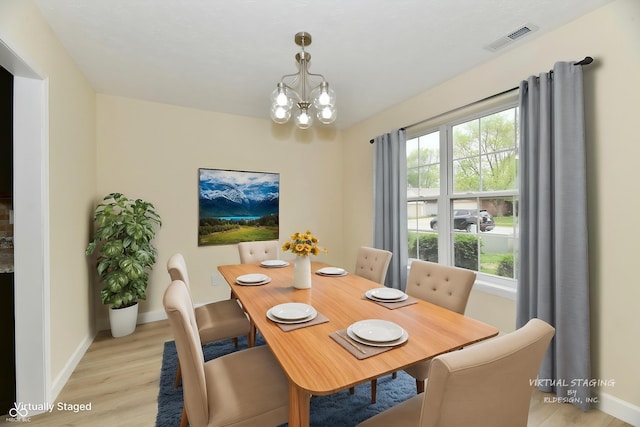 dining space featuring a notable chandelier, baseboards, visible vents, and light wood-style flooring
