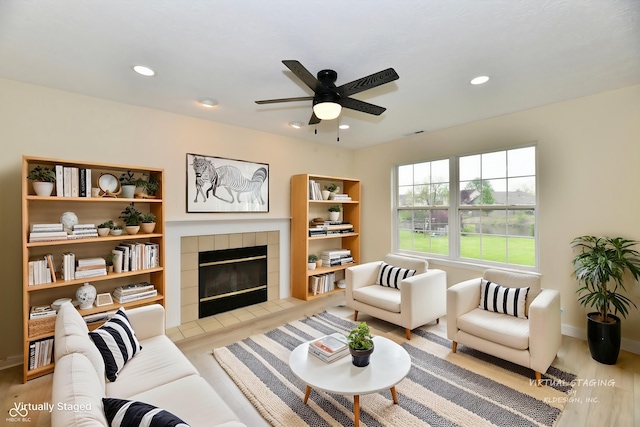 living area featuring a ceiling fan, visible vents, a tile fireplace, light wood-style floors, and recessed lighting