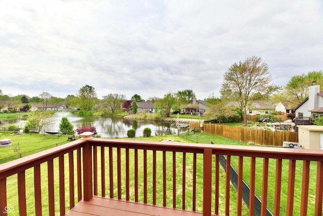 wooden terrace with a lawn, a water view, a residential view, and a fenced backyard