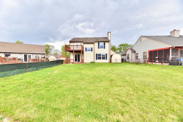 back of house with a lawn, a chimney, a sunroom, and a fenced backyard