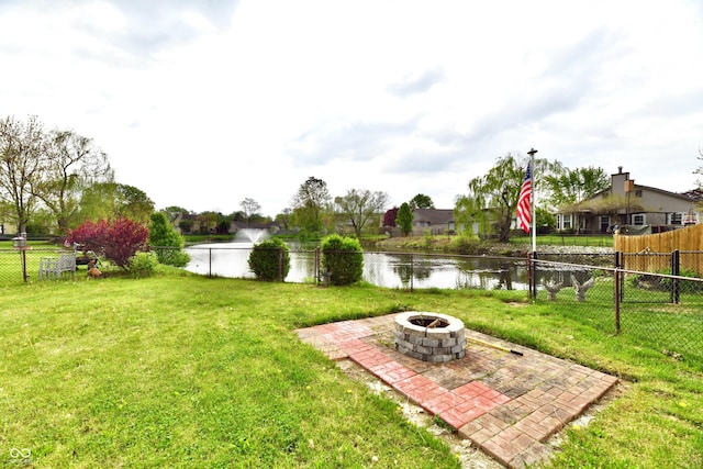 view of yard with a water view, fence, a patio, and an outdoor fire pit