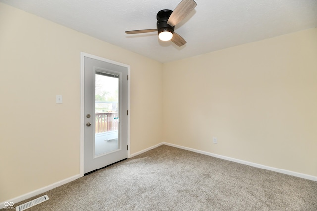 spare room with carpet flooring, a ceiling fan, baseboards, and visible vents