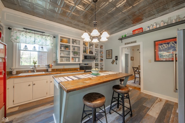 kitchen with crown molding, an ornate ceiling, dark wood finished floors, a sink, and wood counters