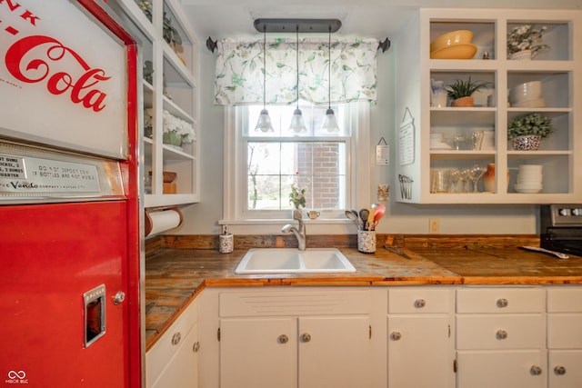 kitchen featuring butcher block countertops, a sink, and white cabinets