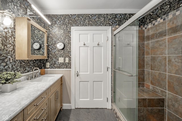 full bathroom with vanity, ornamental molding, wainscoting, wallpapered walls, and a stall shower