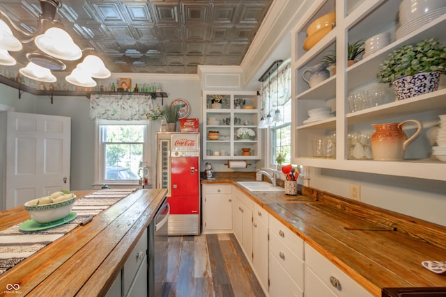 kitchen featuring open shelves, a sink, an ornate ceiling, butcher block countertops, and dark wood finished floors