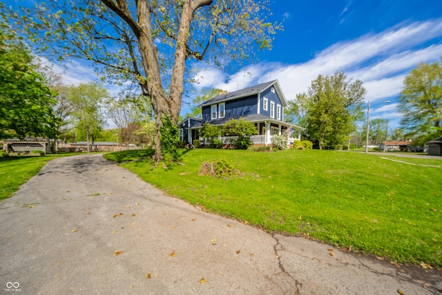 view of home's exterior with a porch, a yard, and concrete driveway