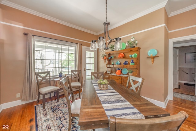 dining room featuring crown molding, baseboards, and wood finished floors