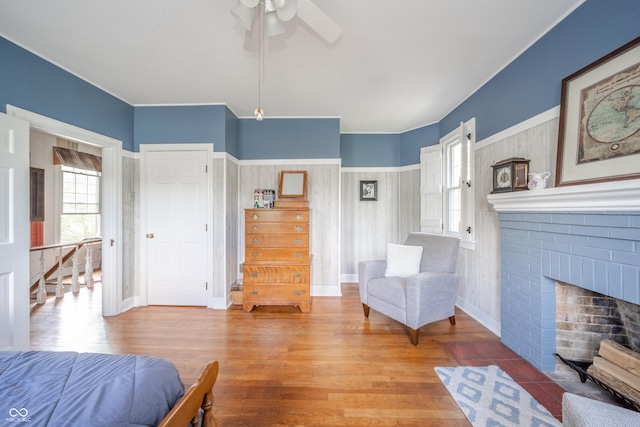 bedroom with a ceiling fan, multiple windows, wood finished floors, and a fireplace