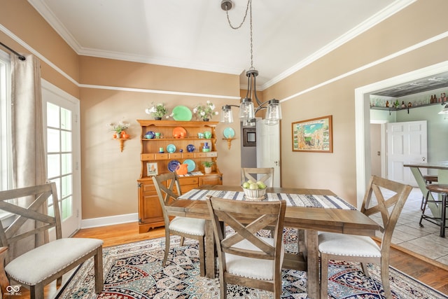 dining area featuring crown molding, baseboards, and light wood finished floors