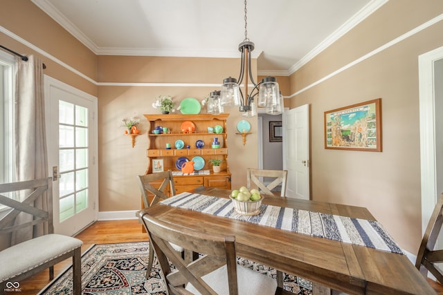 dining space featuring light wood-type flooring, ornamental molding, baseboards, and a notable chandelier