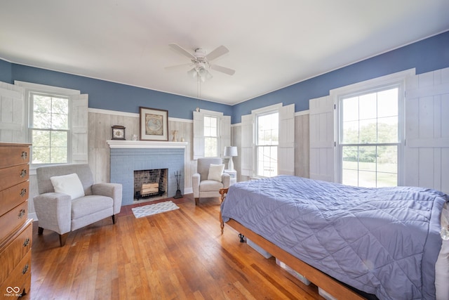 bedroom with a ceiling fan, a brick fireplace, and hardwood / wood-style floors