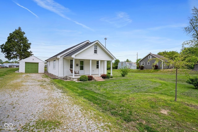 bungalow-style house with covered porch, driveway, an outbuilding, a detached garage, and a front lawn