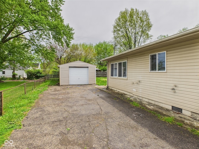 979 Monroe St, Indianapolis, IN 46229 - view of side of property featuring fence, an outdoor structure, aphalt driveway, and a garage