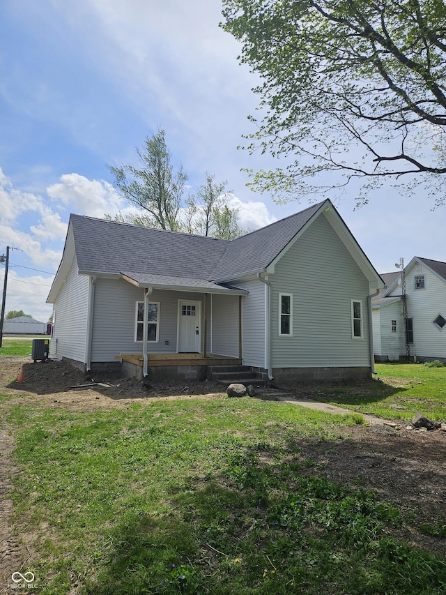 single story home featuring covered porch, cooling unit, roof with shingles, and a front lawn