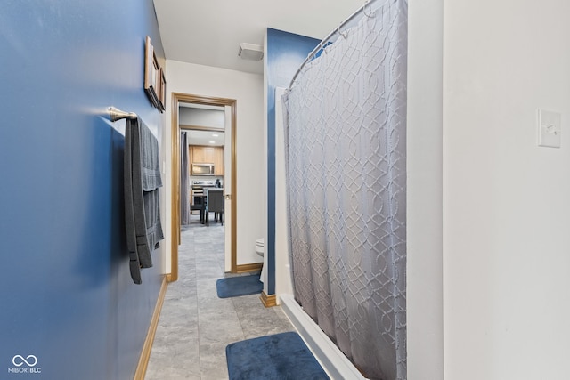 full bath with baseboards, toilet, and curtained shower