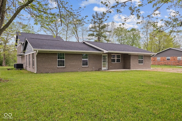 rear view of house featuring a patio, a lawn, central air condition unit, a shingled roof, and brick siding