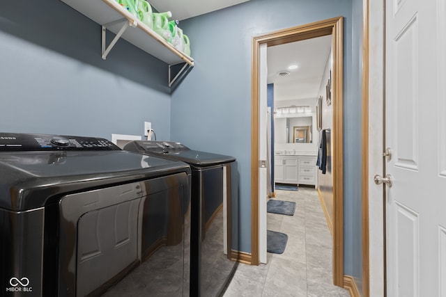 laundry area featuring independent washer and dryer, light tile patterned floors, baseboards, and laundry area