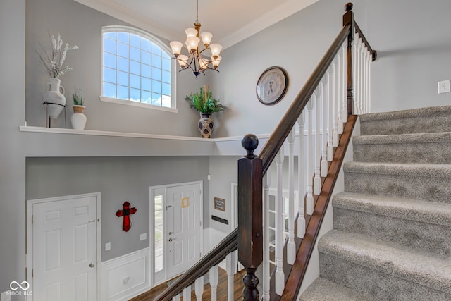 stairway featuring ornamental molding, a chandelier, and wood finished floors