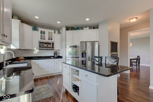 kitchen featuring stainless steel appliances, a sink, a kitchen bar, white cabinetry, and recessed lighting