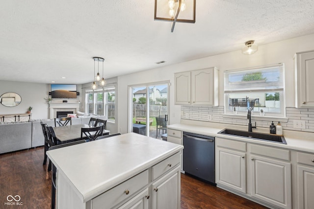 kitchen with backsplash, a textured ceiling, a fireplace, dishwasher, and a sink