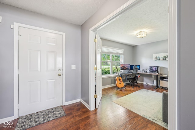 foyer featuring a textured ceiling, baseboards, and wood finished floors