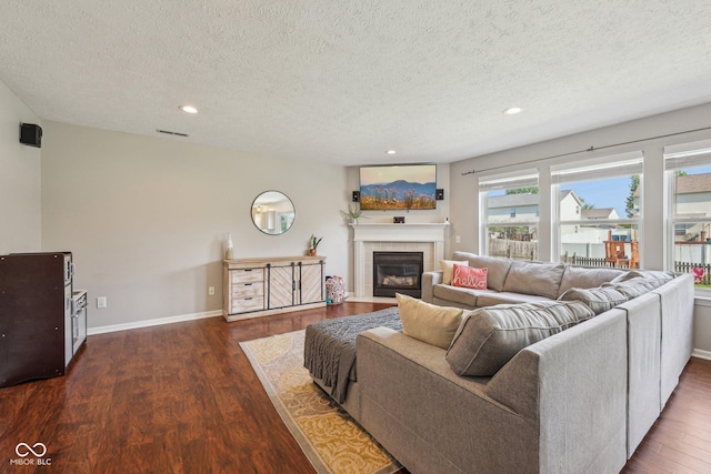 living area with a textured ceiling, visible vents, wood finished floors, a tile fireplace, and recessed lighting