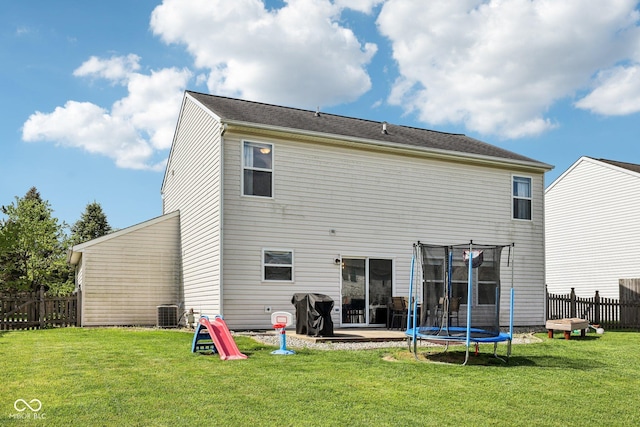 rear view of property with a lawn, fence, and a trampoline