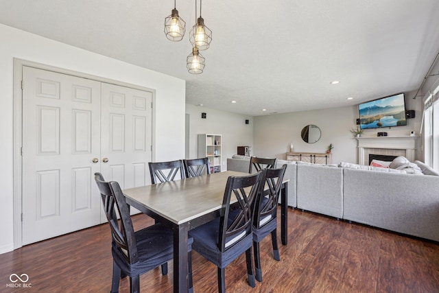 dining area with recessed lighting, dark wood-style flooring, and a fireplace
