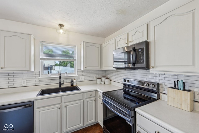 kitchen with backsplash, white cabinetry, appliances with stainless steel finishes, and a sink