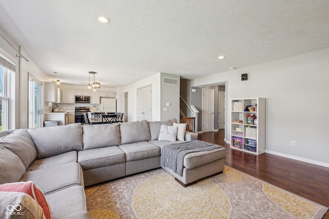 living room with recessed lighting, baseboards, wood finished floors, and a textured ceiling