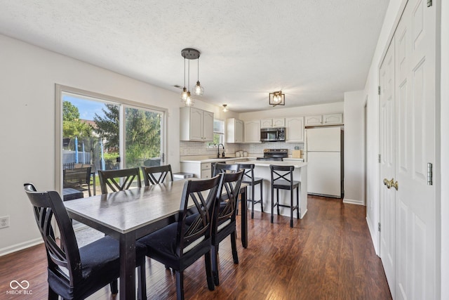 dining area featuring baseboards, dark wood-style flooring, and a textured ceiling