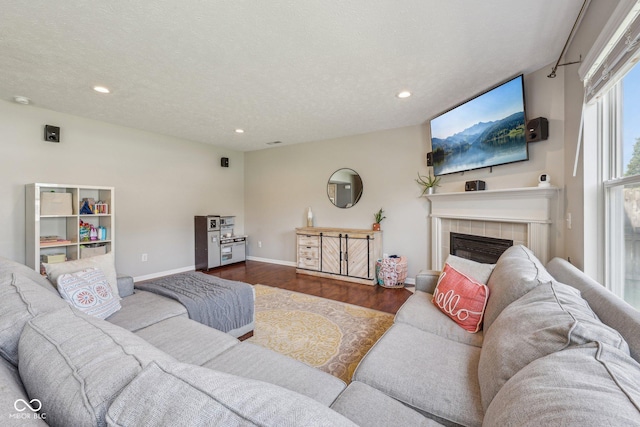 living area with a tiled fireplace, recessed lighting, baseboards, and wood finished floors