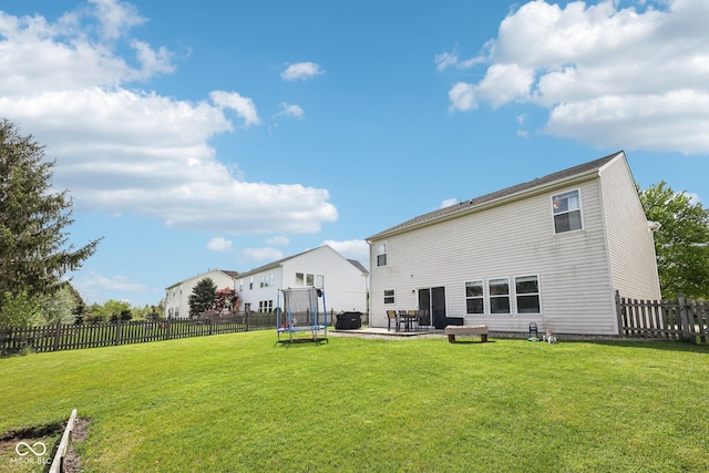 rear view of house featuring a fenced backyard, a trampoline, a yard, and a patio