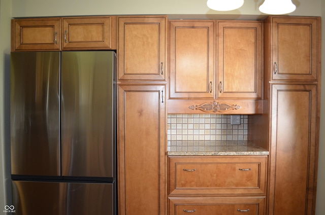 931 Beech Dr, Greenwood, IN 46142 - kitchen with stainless steel fridge, tasteful backsplash, and brown cabinetry