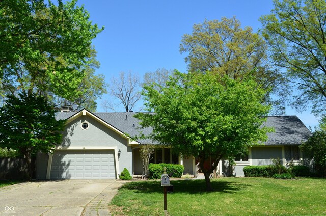 931 Beech Dr, Greenwood, IN 46142 - view of front of home featuring a garage, a front lawn, concrete driveway, a shingled roof, and stucco siding