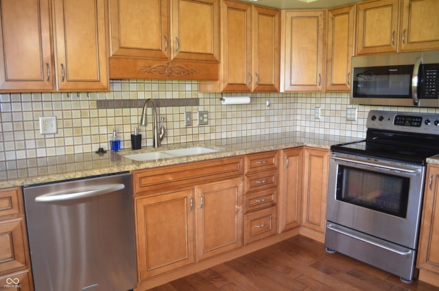 931 Beech Dr, Greenwood, IN 46142 - kitchen with brown cabinets, appliances with stainless steel finishes, a sink, decorative backsplash, and dark wood-style floors