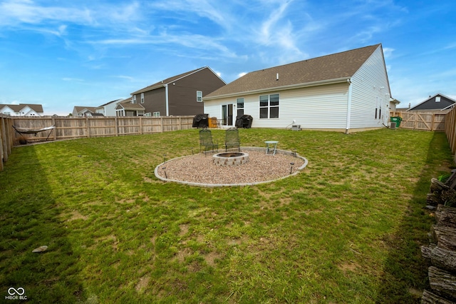 rear view of property with a fenced backyard, a yard, and a fire pit