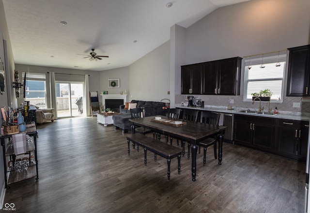 dining room featuring dark wood finished floors, ceiling fan, vaulted ceiling, and a fireplace