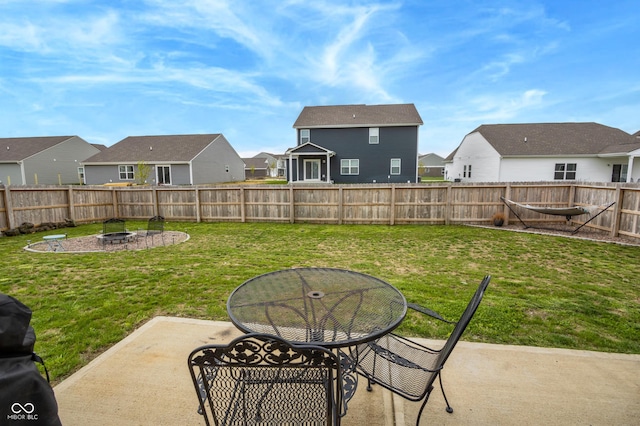 view of yard featuring a patio, a residential view, a fenced backyard, and an outdoor fire pit
