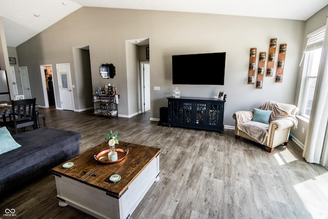 living room with baseboards, wood finished floors, and high vaulted ceiling