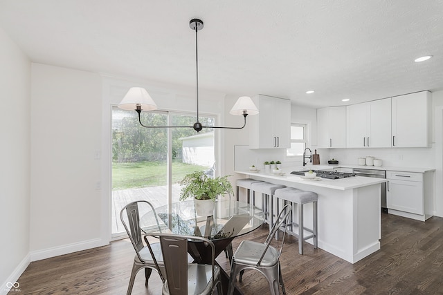 kitchen with light countertops, a peninsula, dark wood-style flooring, and white cabinetry