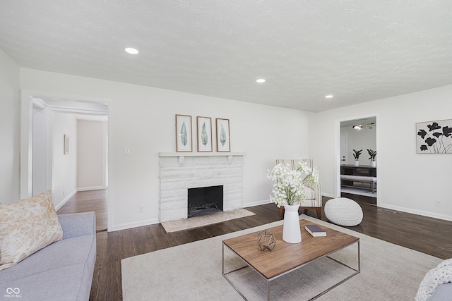living area with wood finished floors, a fireplace, baseboards, recessed lighting, and a textured ceiling