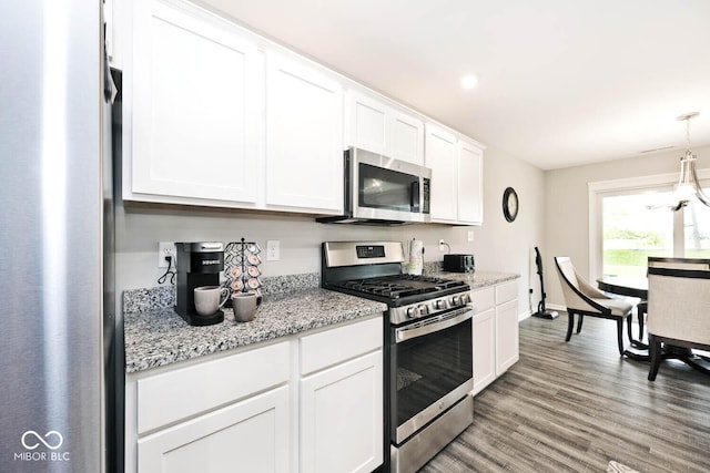 kitchen with light wood-type flooring, baseboards, white cabinets, light stone counters, and stainless steel appliances