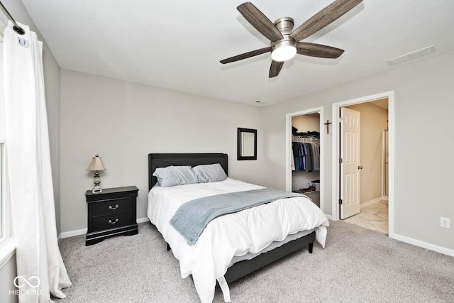 carpeted bedroom with baseboards, a spacious closet, ceiling fan, and visible vents